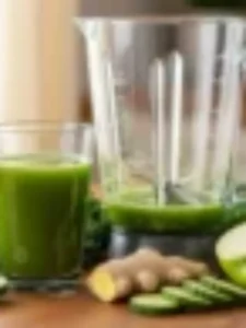 Copo de suco verde detox com pepino, gengibre, couve e maçã ao lado.
